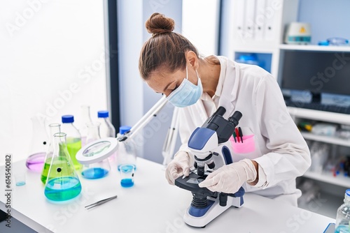 Young woman scientist using microscope working at laboratory