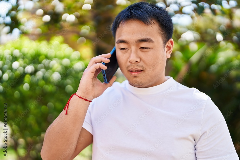 Young chinese man talking on the smartphone at park Young chinese man talking on the smartphone at park