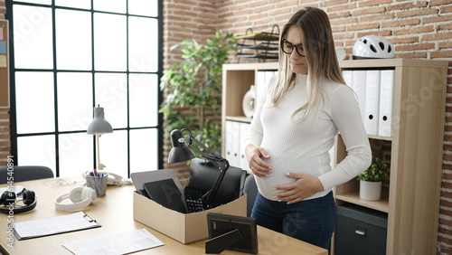 Young pregnant woman being fired packing belongings from workplace touching belly at office © Krakenimages.com