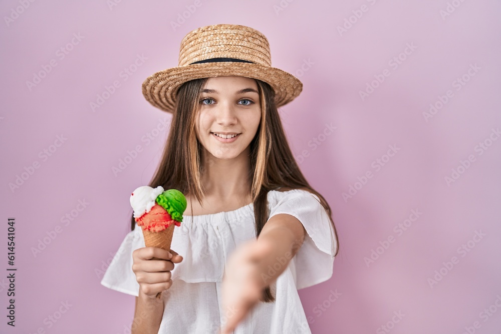 Teenager girl holding ice cream smiling friendly offering handshake as greeting and welcoming. successful business.