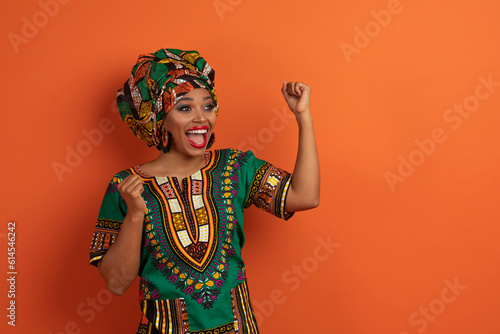 Emotional thrilled young black woman gesturing on orange, copy space