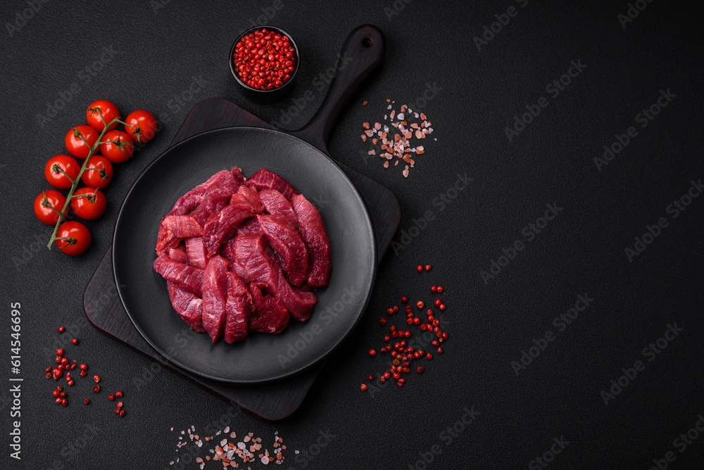 Juicy raw beef with spices, salt and herbs on a dark concrete background Juicy raw beef with spices, salt and herbs on a dark concrete background