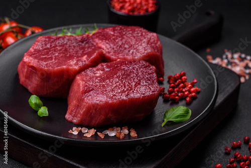 Juicy raw beef with spices, salt and herbs on a dark concrete background
