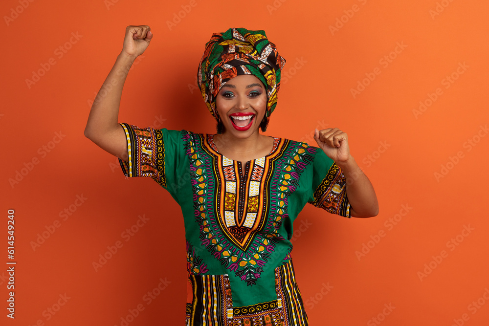 Obraz premium Super happy young african lady celebrating success win on orange