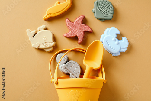 Silicone beach toys, bucket, shovel on sand color background. photo