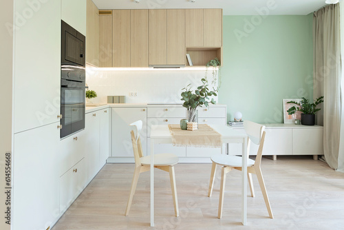 Modern interior of kitchen with dining room. Stylish furniture with oven and table and chairs on the wooden floor. Luxury in indoor architecture in the room.