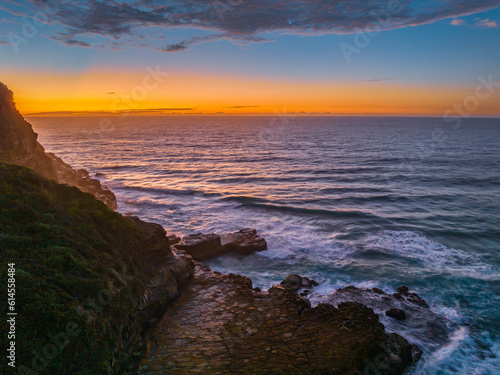 Ocean sunrise with rock platform and clouds