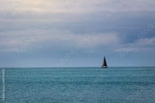 segelboot am horizont in einem blauen meer bei blauen himmel und strahlender sonne mit wolken