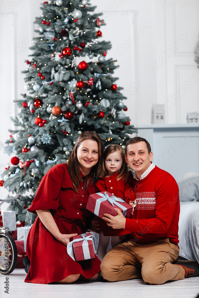 Happy caucasian family sits under the Christmas tree and opens gifts Happy caucasian family sits under the Christmas tree and opens gifts