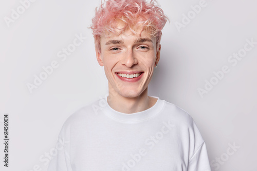 Portrait of handsome pink haired man dressed in casual clothes smiles gladfully concentrated into camera expresses positive emotions isolated over white background. People and face expressions concept