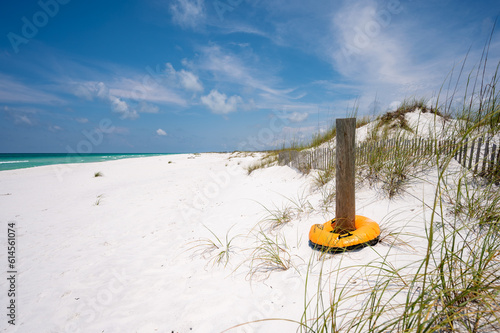 Shell Island Beach, white sand, blue sky with yellow tube around wooden post with wooden fence