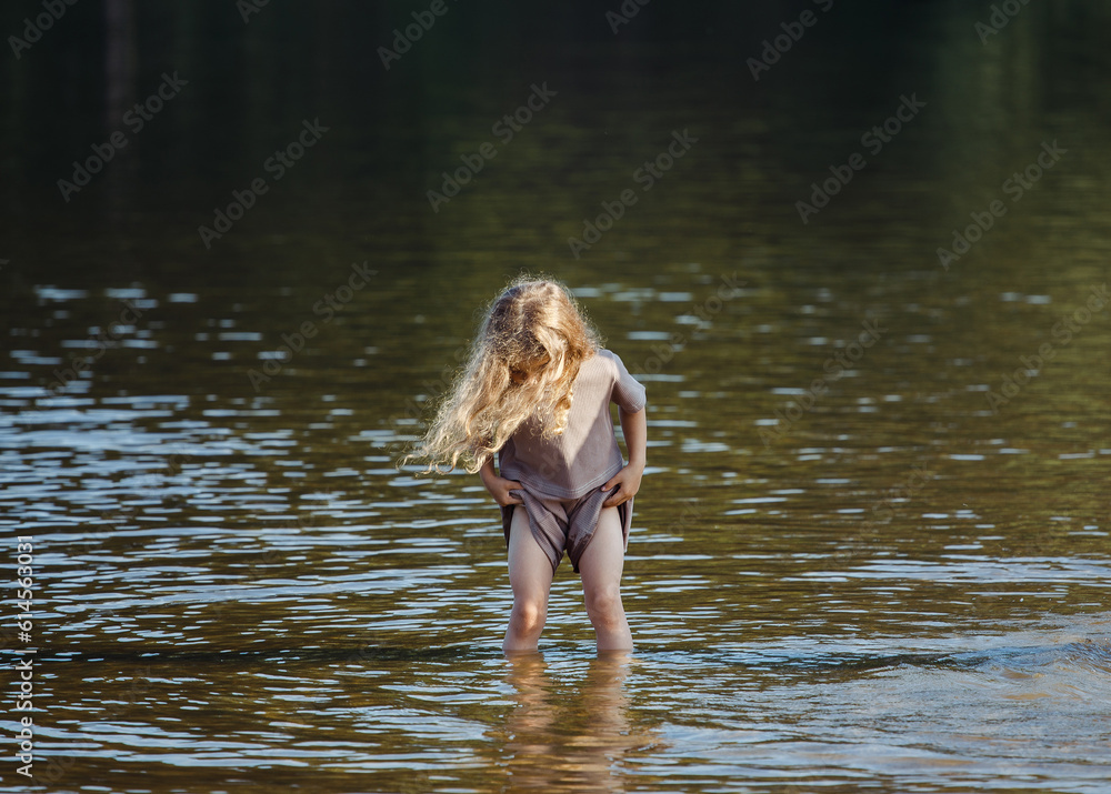 Fototapeta premium A five year old girl is playing on the beach. Happy childhood.