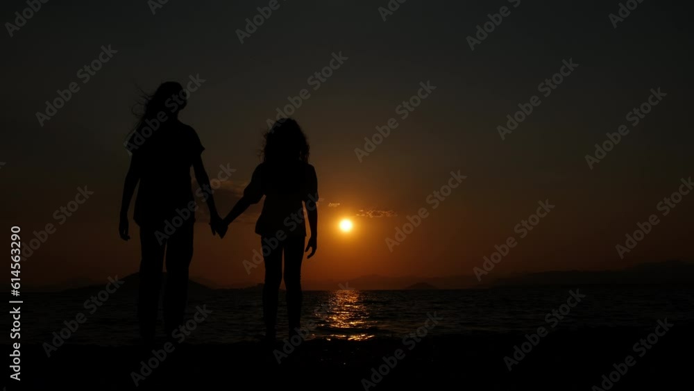Children at sunset. Silhouette of two young girls holding hands against the backdrop of a sea sunset. Children at sunset. Silhouette of two young girls holding hands against the backdrop of a sea sunset.