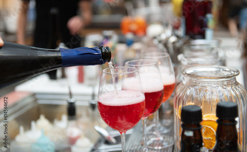 Pouring red cocktail in glasses aligned on bar counter detail