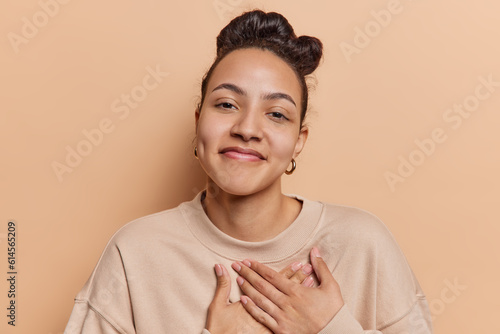 Foto Photo of pleased Latin woman tenderly places her hands on heart conveying profou