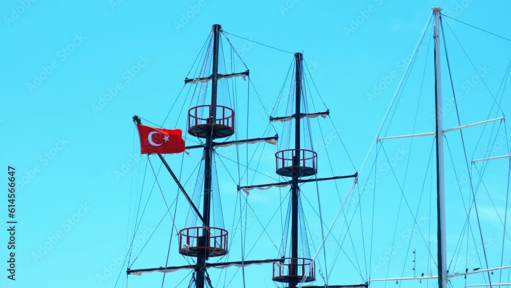 Moored ship with mast against sky. A moored ship with turkey flag on the mast stay in the summer sun against blue clear sky. Moored ship with mast against sky. A moored ship with turkey flag on the mast stay in the summer sun against blue clear sky.