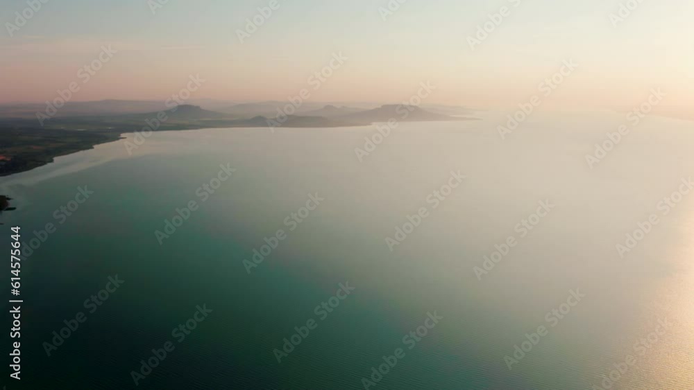 Landscape and Sunset above Lake Balaton with Calm waves in Hungary, Central Europe. Panoramic View of Coast with water reflecting Sun with hills at back in Transdanubian region. 4k drone shot Landscape and Sunset above Lake Balaton with Calm waves in Hungary, Central Europe. Panoramic View of Coast with water reflecting Sun with hills at back in Transdanubian region. 4k drone shot