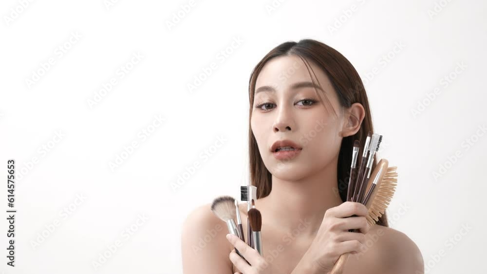 Beauty concept of 4k Resolution. Asian woman smiling with confidence in makeup with a brush on a white background. Beauty concept of 4k Resolution. Asian woman smiling with confidence in makeup with a brush on a white background.