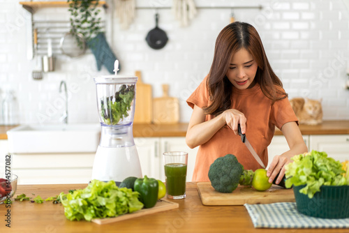 Portrait of beauty healthy asian woman making green vegetables detox cleanse and green fruit smoothie with blender.young girl drinking glass of smoothie, fiber, chlorophyll in kitchen.Diet, healthy