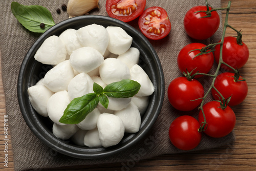 Delicious mozzarella balls, tomatoes and basil leaves on wooden table, flat lay