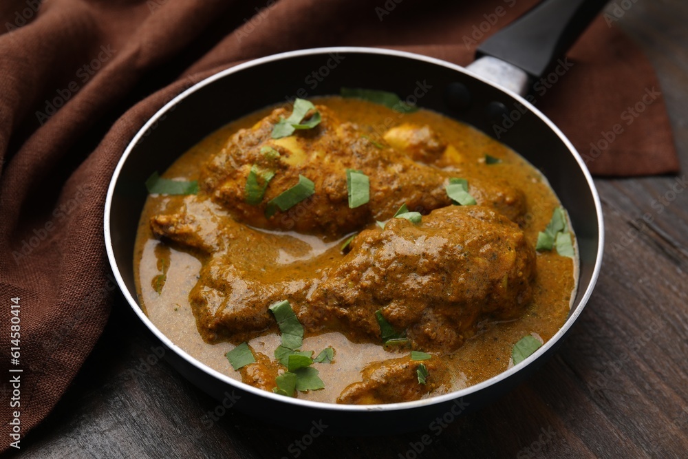 Fototapeta premium Delicious chicken with curry sauce on wooden table, closeup