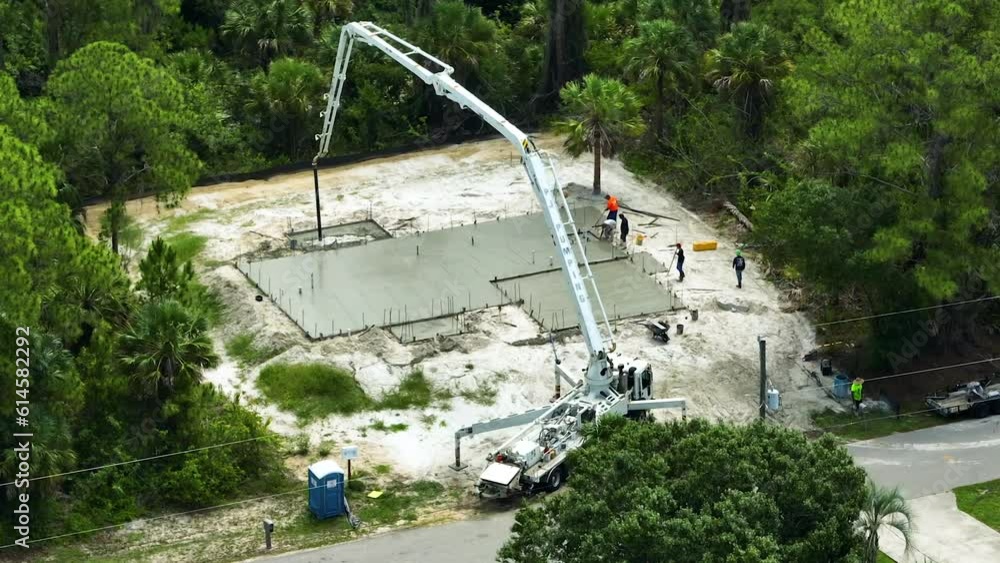Aerial view of workers at new house construction site pouring concrete of flat slab foundation bedding ready for building walls and roof Aerial view of workers at new house construction site pouring concrete of flat slab foundation bedding ready for building walls and roof