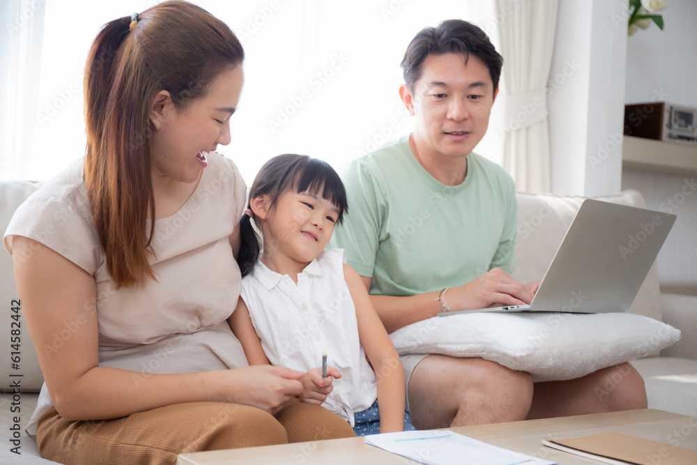 Happy family with mother teaching homework with daughter and father working with laptop on sofa in living room at home, mom explaining schoolwork with kid together, lifestyles and education. Happy family with mother teaching homework with daughter and father working with laptop on sofa in living room at home, mom explaining schoolwork with kid together, lifestyles and education.