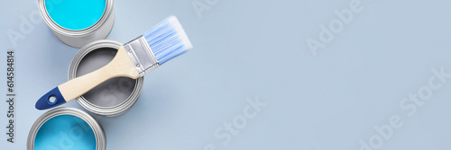 Cans with different paints and brush on light background, flat lay. Banner design with space for text