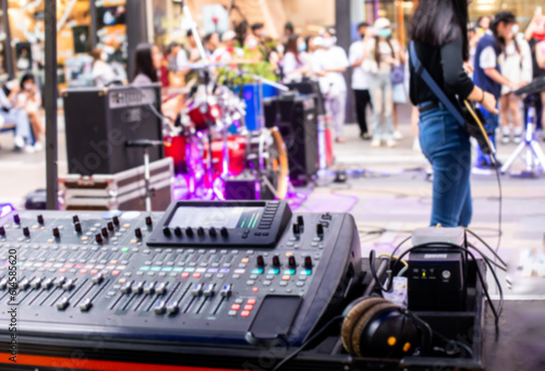 Blurry picture of smart sound mixer board and musician in concert event.