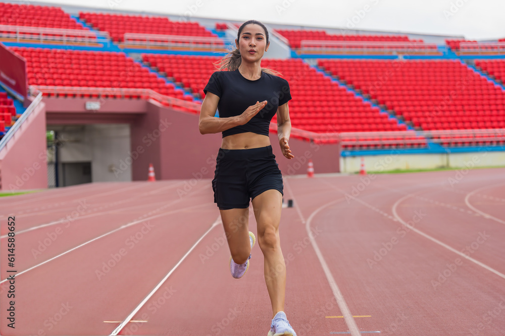 Fototapeta premium Asian female athlete accelerates during her speed running practice on the stadium track, embodying determination