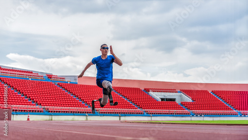 Asian male athlete with prosthetics runs at full speed, demonstrating a powerful practice on stadium track