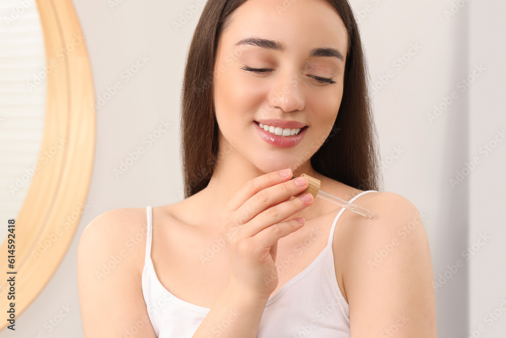 Woman applying essential oil onto shoulder in bathroom, closeup Woman applying essential oil onto shoulder in bathroom, closeup