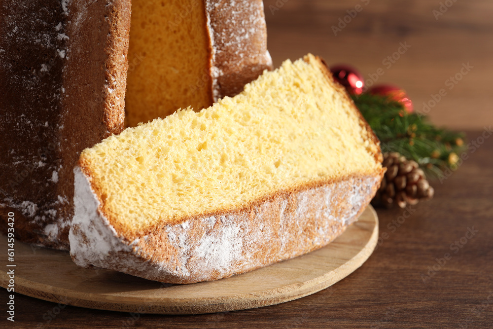 Delicious Pandoro cake with powdered sugar and Christmas decor on wooden table, closeup. Traditional Italian pastry