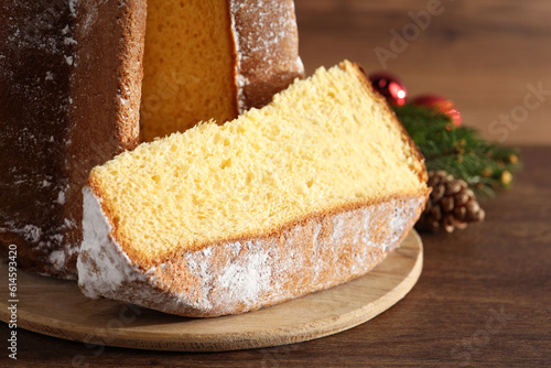 Delicious Pandoro cake with powdered sugar and Christmas decor on wooden table, closeup. Traditional Italian pastry