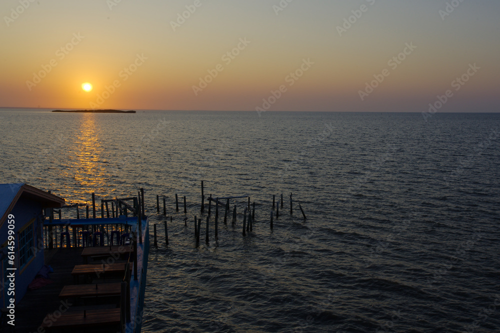 Sunrise overlooking Fishing dock in Cedar Key Florida. On a sunny day with calm waters. Wood pier poles in water with dim lights.
