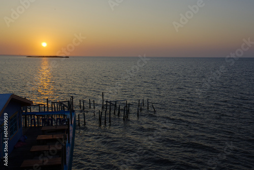 Sunrise overlooking Fishing dock in Cedar Key Florida. On a sunny day with calm waters. Wood pier poles in water with dim lights.