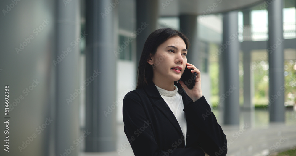 Young Asian businesswoman in suit talking on smartphone at modern office Young Asian businesswoman in suit talking on smartphone at modern office