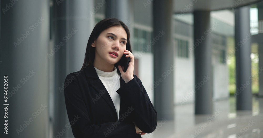 Young Asian businesswoman in suit talking on smartphone at modern office Young Asian businesswoman in suit talking on smartphone at modern office