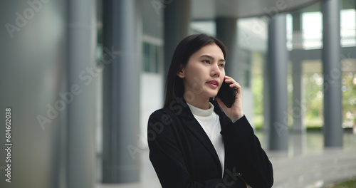 Young Asian businesswoman in suit talking on smartphone at modern office