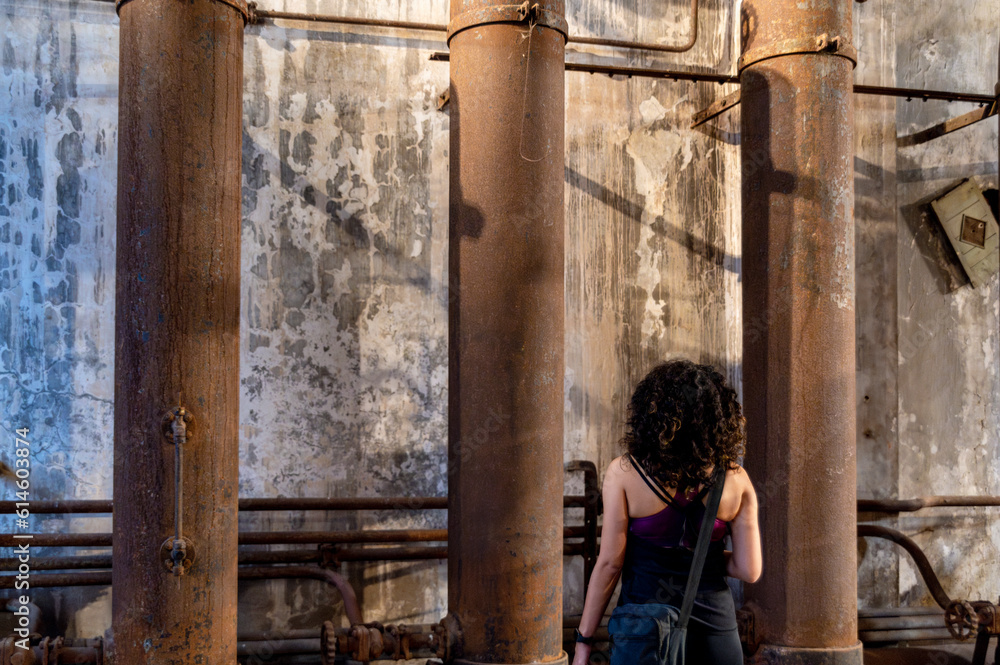 Back view of a woman exploring an old abandoned factory.