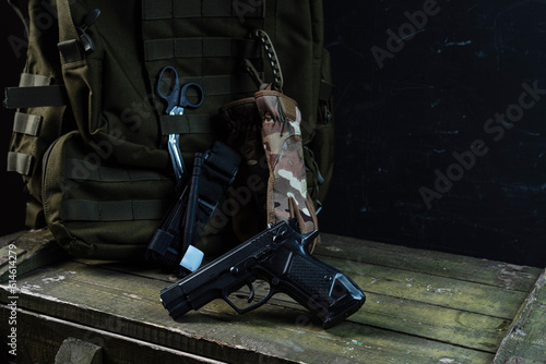 A pistol on the background of a military backpack. Military backpack and paramedic tools. Military doctor.
