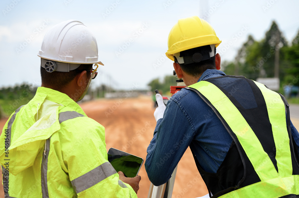 Asian surveyor engineer two people checking level of soil with Surveyor's Telescope equipment to measure leveling for cut and fill, started leveling the ground at the highway road construction site. Asian surveyor engineer two people checking level of soil with Surveyor's Telescope equipment to measure leveling for cut and fill, started leveling the ground at the highway road construction site.
