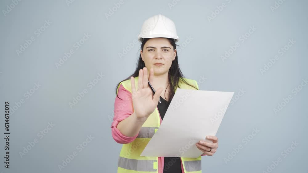 The engineer looks at the camera and makes a stop sign. The engineer looks at the camera and makes a stop sign.