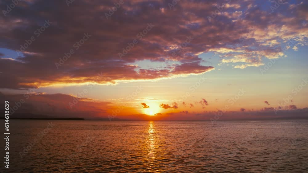 Delicate background of sea sunset, view from the beach. The setting sun in the blue sky with orange clouds over the Caribbean Sea. Beautiful summer seascape. Evening sun glare on the water. Delicate background of sea sunset, view from the beach. The setting sun in the blue sky with orange clouds over the Caribbean Sea. Beautiful summer seascape. Evening sun glare on the water.