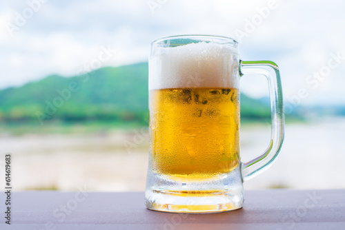 Glass of light beer on a table with nature background.