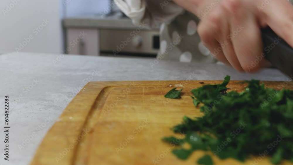 Chop the parsley on a board, greens for the dish. close-up process Chop the parsley on a board, greens for the dish. close-up process