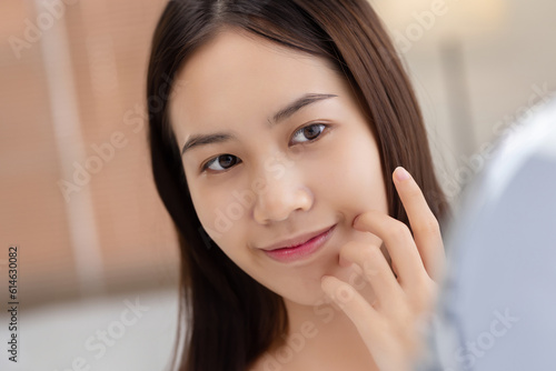 Closeup portrait of young beautiful Asian girl with mirror makeup routine. Healthcare woman lifestyle facial skin care concept.
