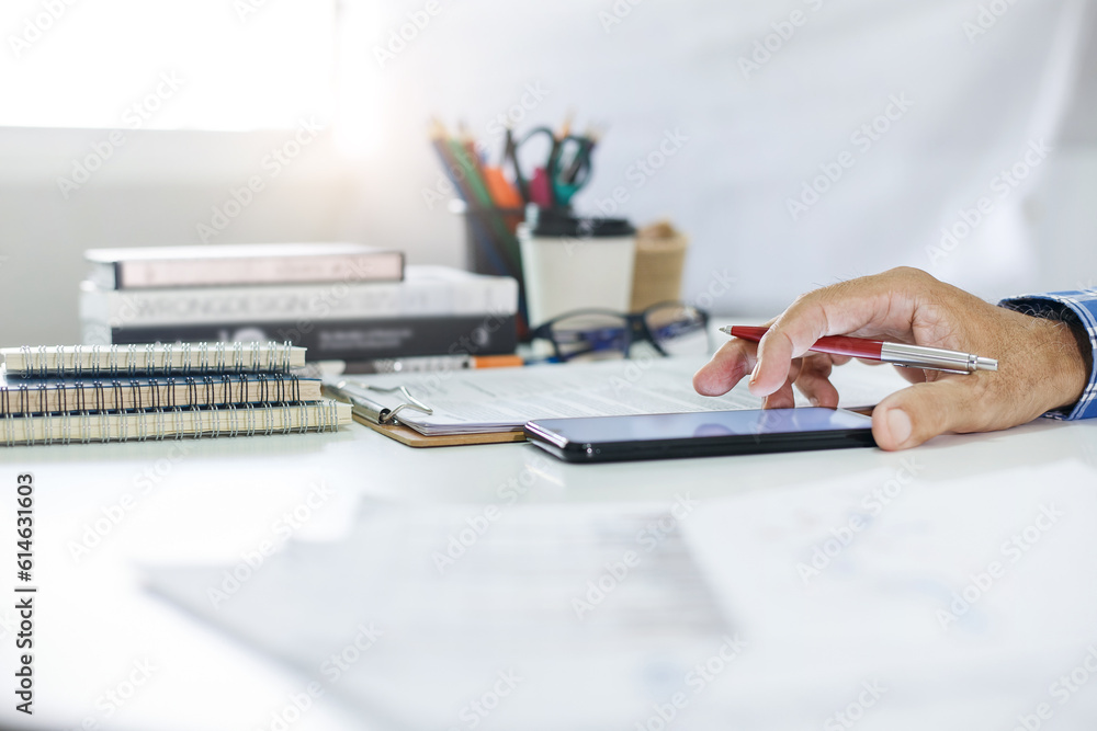 Hand of businessman investor working on dest at home use smartphone and holding pen checking financial reports or business contract via mobile, Concept working at home by remotely online Hand of businessman investor working on dest at home use smartphone and holding pen checking financial reports or business contract via mobile, Concept working at home by remotely online
