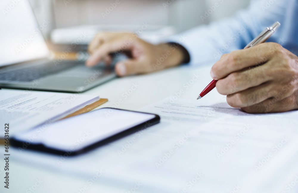 Businessman investor checking financial report or business contract from documents lying on his desk, A man working or meeting online with computer laptop on desk at home, Select focus at pen in hand Businessman investor checking financial report or business contract from documents lying on his desk, A man working or meeting online with computer laptop on desk at home, Select focus at pen in hand