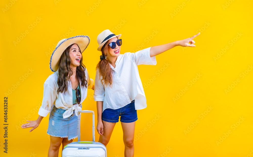 Two Pretty asian women passenger in trendy fashion is exciting to board while carrying her luggage bag in happiness for friendly trip and summer travel vacation isolated on yellow background Two Pretty asian women passenger in trendy fashion is exciting to board while carrying her luggage bag in happiness for friendly trip and summer travel vacation isolated on yellow background